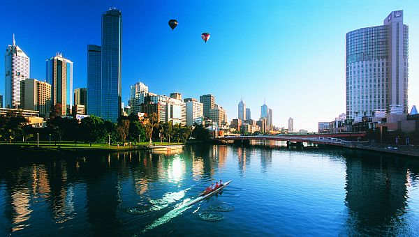 Rowers and hot air balloons over Melbourne skyline and Yarra River